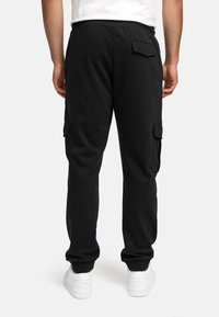 Pantalones cargo negros con cintura elástica y puños elásticos, que cuentan con bolsillos laterales y un bolsillo trasero, hechos de una tela suave y transpirable.