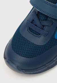 Chaussure de sport bleu marine avec tige en mesh et en cuir synthétique, dotée d'une bande Velcro et d'une semelle extérieure texturée, conçue pour le confort.