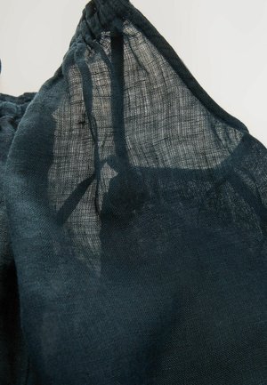 Tumši zaļš, caurspīdīgs audums ar teksturētu, austu rakstu, ar savilktu kakla izgriezumu. Viegls un caurspīdīgs izskats.