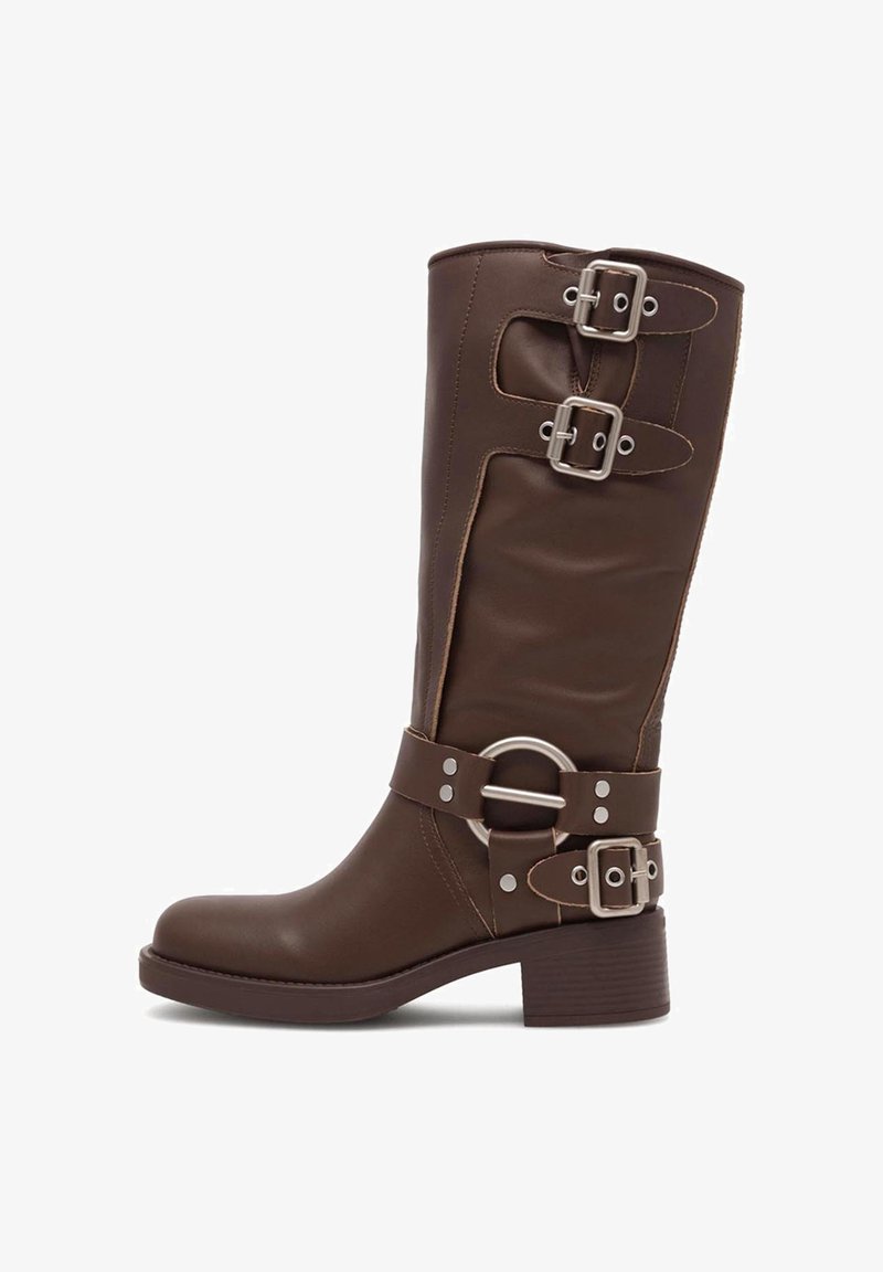 Botină din piele maro, până la genunchi, cu vârful rotund, multiple catarame decorative, accent de hardware circular și toc căptușit.