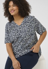 Top corto a maniche corte blu e bianco con scollatura a V, realizzato in tessuto morbido. Presenta leggere arricciature vicino alla scollatura.