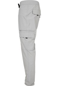 Helle graue Cargo-Hosen aus Nylon mit einem elastischen Bund, mehreren Seitentaschen und einer Reißverschlusstasche am Oberschenkel.