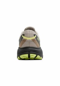 Chaussure de course beige et noire avec une tige texturée, un accent jaune et une semelle à motifs. Comprend un col rembourré et un logo visible.