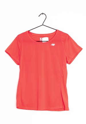Czerwona sportowa koszulka z krótkimi rękawami, okrągłym dekoltem i gładką fakturą. Na górnej lewej stronie klatki piersiowej znajduje się małe białe logo.