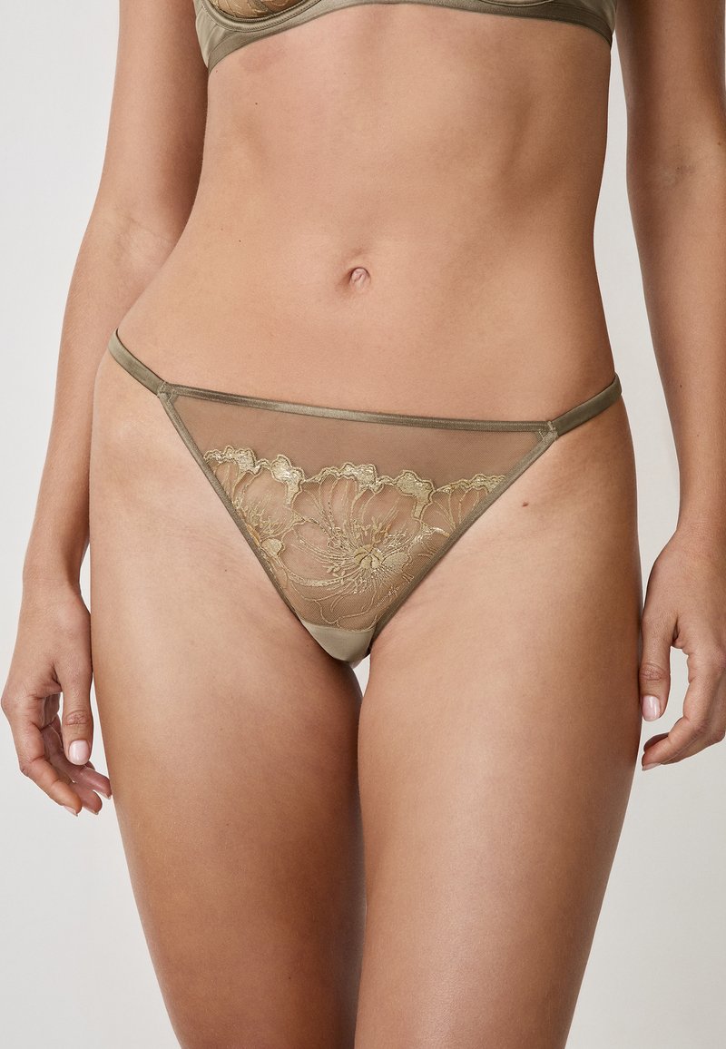 Tanga trasparente verde oliva con delicati ricami floreali dorati. Presenta sottili spalline e un elastico liscio in satin in vita. Texture morbida e copertura minima.