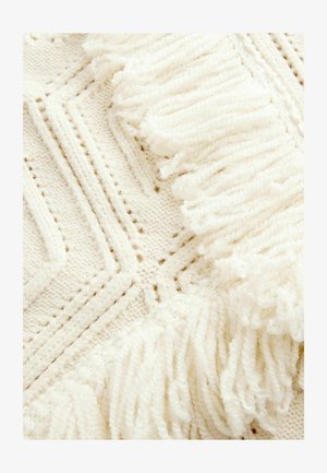 Couverture tricotée en crème avec des motifs géométriques, présentant des franges texturées le long d'un bord, mettant en valeur des fils doux et duveteux.