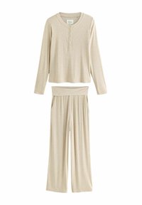 Haut à manches longues rayé beige avec patte de boutonnage et pantalon à jambes larges présentant une taille élastique. Texture douce tout au long.