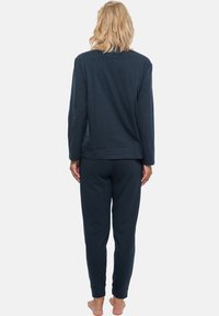 Navyblå långärmad topp och matchande byxor i mjukt material, med avslappnad passform och rundad halsringning, samt uppvikt byxmuddar.