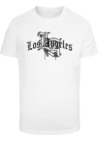 Bílý bavlněný tričko s černým textovým designem ve stylu graffiti "Los Angeles", s kapkami a složitým písmem.