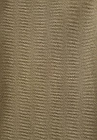 Tessuto di cotone in una tonalità marrone chiaro, caratterizzato da un delicato motivo a diagonale. Texture liscia, con leggere variazioni di colore.
