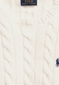Pull en maille torsadée blanc avec étiquette Polo Ralph Lauren marine et petit logo joueur de polo brodé en marine sur le tissu.