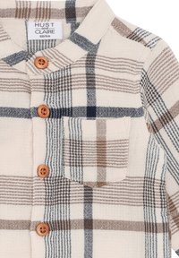 Camicia con bottoni in fantasia a quadri beige, marrone e blu navy, con bottoni in legno e una tasca sul petto. Realizzata in tessuto intrecciato.