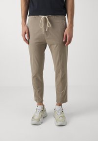 Beige broek met rechte pijpen en een tailleband met koord, met zijzakken, gemaakt van een lichte stof, in combinatie met chunky sneakers.