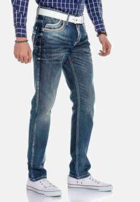 Blauwe denim jeans met een klassieke pasvorm, vervaagde wassing, contrasterende stiksels en een vijf-pocket ontwerp, gecombineerd met witte sneakers.