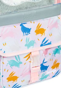 Plecak dziecięcy z pastelowego materiału w zajączki w kolorze niebieskim, różowym, zielonym i pomarańczowym, z miękkim szarym paskiem u góry i różowym paskiem.