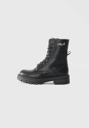 Black leather lace-up boots with a chunky sole, featuring a decorative silver chain at the top and a pull tab at the back.