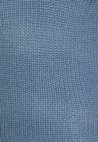 Texturerad stickad tyg i ljusblått, med ett regelbundet mönster och jämna stygn, vilket ger ett mjukt och något stretchigt utseende.