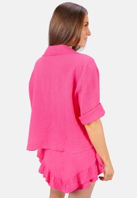 Rosa Baumwoll-Koordinations-Set mit einem lockeren, strukturierten Oberteil mit umgeschlagenen Ärmeln und einem Rock mit Rüsche. Einfaches, lässiges Design.