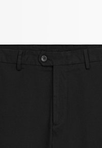 Zwart formele broek met een tailleband, knoopsluiting, riemlussen en een verborgen ritsdetail.