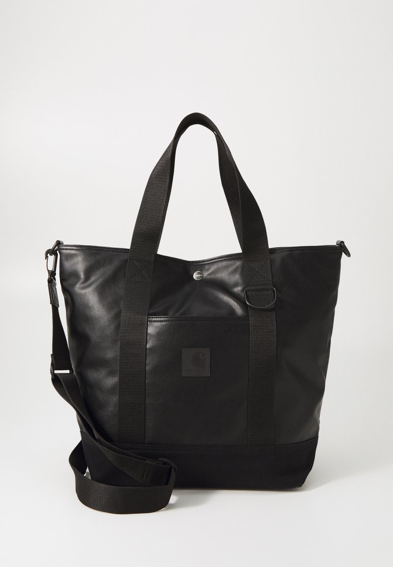 Sac fourre-tout noir en matériau lisse, avec une poche carrée à l'avant, des poignées courtes doubles et une bandoulière amovible.