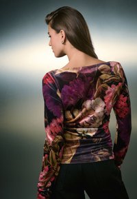 Langärmliges Oberteil mit floralem Muster, das lebendige violette und pinke Blumen auf dunklem Hintergrund zeigt; weicher, dehnbarer Stoff mit einem Bootsausschnitt.