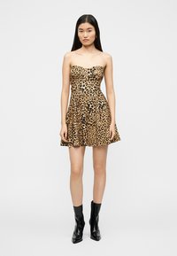 Φόρεμα χωρίς τιράντες με λεοπάρ μοτίβο σε αποχρώσεις του καφέ και του μαύρου, με φούστα που ανοίγει. Το μοντέλο φοράει μαύρα μποτάκια αστραγάλου.