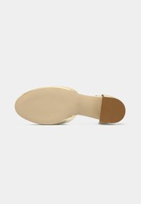 Gyllene klacksandaler med ett slät ovandel, öppen baksida och en ljus beige sula. Klacken är smal med rundad kant och minimal textur.