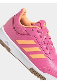 Scarpa da ginnastica sintetica rosa con accenti arancioni e tre strisce laterali. Parte superiore testurizzata con collo imbottito e suola in gomma bianca.