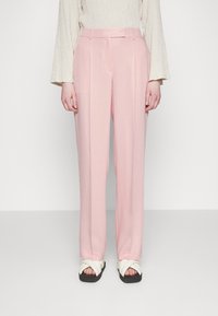 Ljust rosa byxor med skräddarsydd passform, som har en slät yta och subtila veckdetaljer; matchade med vita sandaler med tvärband.