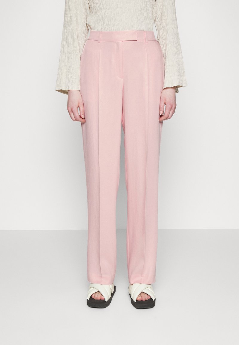 Ljust rosa byxor med skräddarsydd passform, som har en slät yta och subtila veckdetaljer; matchade med vita sandaler med tvärband.