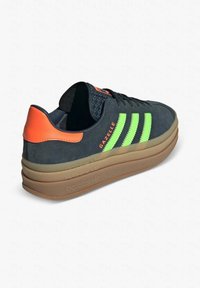 Sneaker in suede blu scuro con strisce verde brillante, dettagli arancioni e suola in gomma. Presenta una linguetta testurizzata e un tallone rinforzato.