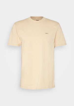 Beige bomulds t-shirt med korte ærmer, rund hals og et lille sort "OBEY" logo på brystet. Glat tekstur, minimal design.