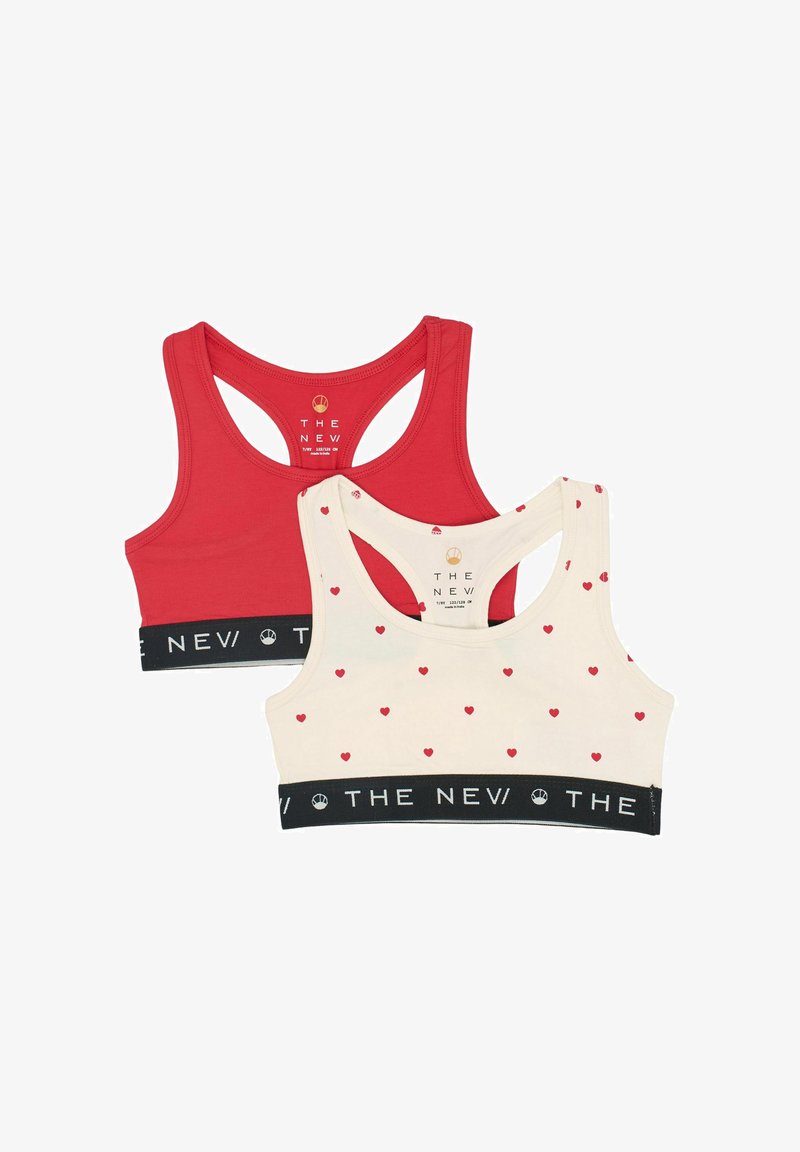 Două sutiene sport: unul roșu, iar celălalt crem cu un mic model de inimioare roșii. Ambele au un bandă elastică neagră cu brand și un design de tip racerback.