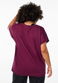 Burgunderrotes Kurzarm-T-Shirt aus einem glatten, elastischen Stoff. Es bietet eine lockere Passform und einen runden Ausschnitt, mit einem längeren hinteren Saum für zusätzliche Bedeckung.