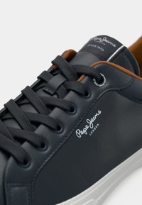 Tamno plavi kožni tenisice s crnim vezicama, bijelim potplatom, smešnim unutarnjim podstavom i bijelim logom "Pepe Jeans London" sa strane i na jeziku.