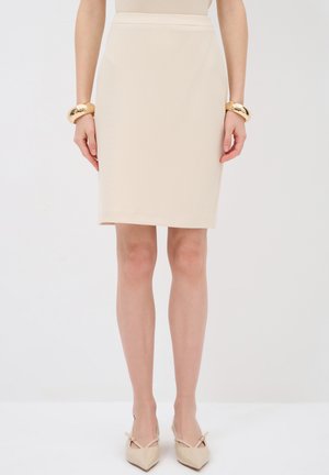 Beige pence-skirt met een gestructureerd patroon, slim fit en een middenlange zoom. Gecombineerd met gouden bangle armbanden en puntige beige hakken.
