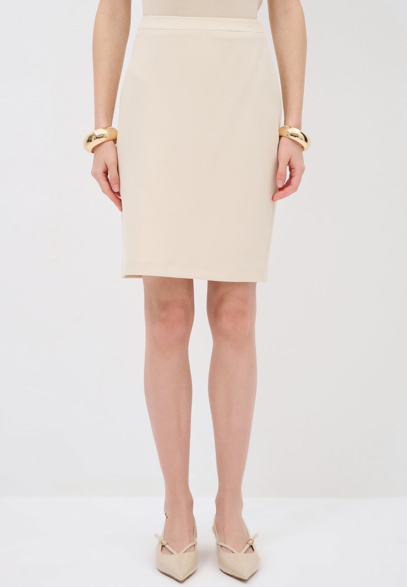 Beige sukně na tužku s texturovaným vzorem, slim fit a střední délkou. V kombinaci se zlatými náramky a špičatými béžovými lodičkami.
