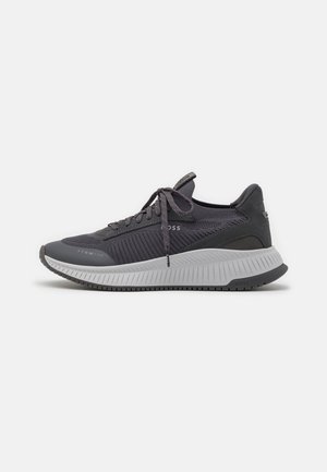 Ciemnoszary sneaker z sznurowadłami, teksturowaną dzianinową cholewką, grubą białą, ryflowaną podeszwą oraz subtelnym nadrukiem marki na boku i podeszwie.