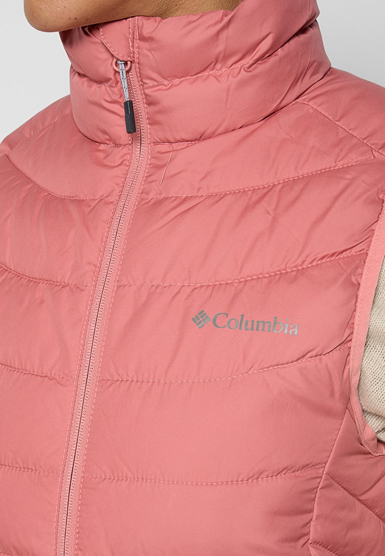 Gilet puffo rosa con colletto alto, caratterizzato da motivi a righe orizzontali, una cerniera frontale e un logo Columbia grigio sul lato sinistro.