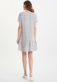 Vestido corto floral de manga corta, con un dobladillo en capas con volantes, en colores claros con un patrón de flores azules y naranjas.