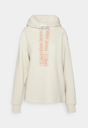Kremowa bluza z kapturem z długimi rękawami i sznurkami, na której nadrukowano napis „Calvin Klein Jeans” w pomarańczowym kolorze.