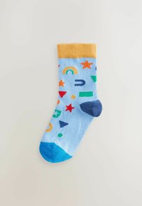Bunt gemusterte Knöchelsocke mit einem hellblauen Grund, gelbem Bündchen und verspielten Mustern von Sternen, Formen und einem Regenbogen in Rot, Grün und Blau.