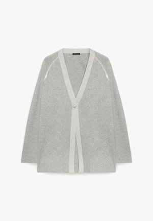 Světlá šedá kardigan se sponou na jedno ozdobné tlačítko, výstřihem do V a stříbrnou flitrovou ozdobou podél švů na ramenou.