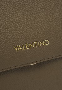 Hnědá kožená kabelka s texturovaným povrchem a zlatým logem "VALENTINO". Obsahuje kontrastní prošití a zavírání na klopu.