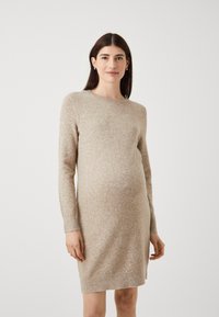Abito maglione beige con maniche lunghe, scollo rotondo e silhouette aderente che si adatta a una pancia in crescita. Tessuto texturizzato.