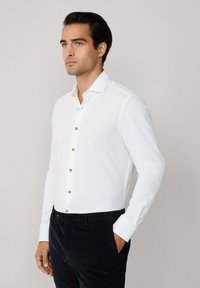Witte lange mouwen shirt met een slim fit, uitgerust met koperen knopen, een klassieke kraag en contrasterende manchetten, gecombineerd met marineblauwe corduroy broek.