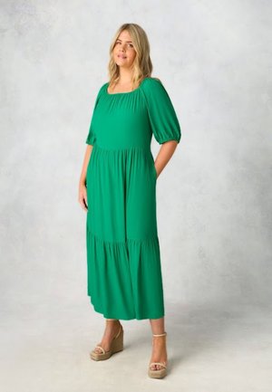 Groene midi-jurk met een vierkante halslijn, korte pofmouwen, een relaxed fit, gelaagd ontwerp en zijzakken. Gecombineerd met sleehakken.