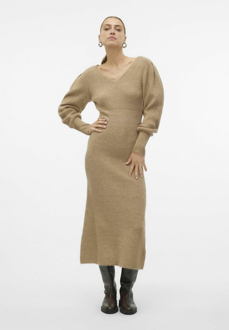 Abito midi in maglia beige con scollatura a V e maniche a sbuffo. Tessuto texturizzato, corpetto aderente e gonna dritta, abbinato a stivali alti scuri.