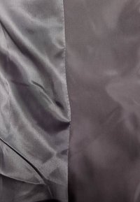 Tissu bicolore avec une texture lisse et brillante à gauche et une texture mate à droite, présentant de légers plis et froissements.