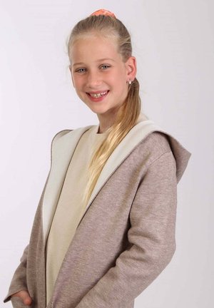Lichtbruine cardigan met een witte capuchon, zachte textuur, lange mouwen en voorzakken, gedragen over een beige shirt.